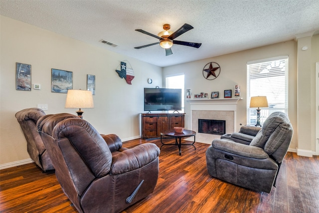 living room with a textured ceiling, a fireplace, a healthy amount of sunlight, and dark hardwood / wood-style floors