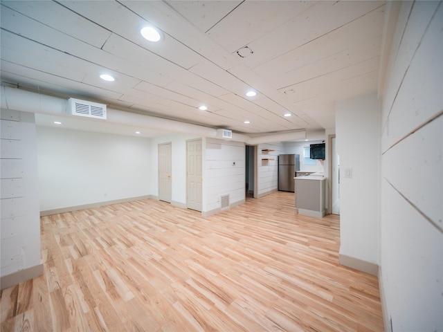 basement featuring stainless steel fridge and light hardwood / wood-style floors