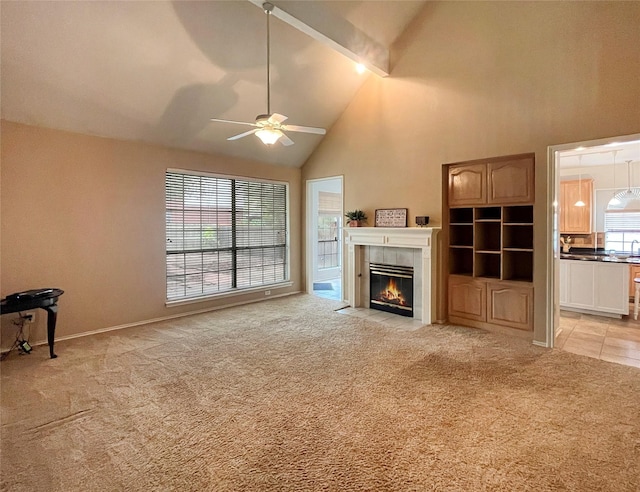 unfurnished living room featuring light carpet, ceiling fan, a tile fireplace, high vaulted ceiling, and beamed ceiling