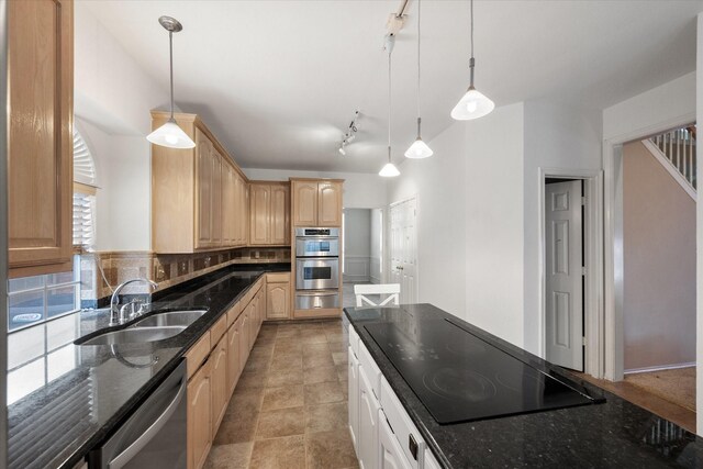 kitchen with light brown cabinetry, stainless steel appliances, sink, dark stone countertops, and hanging light fixtures