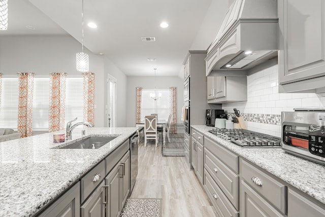 kitchen with premium range hood, sink, gray cabinets, decorative light fixtures, and stainless steel appliances