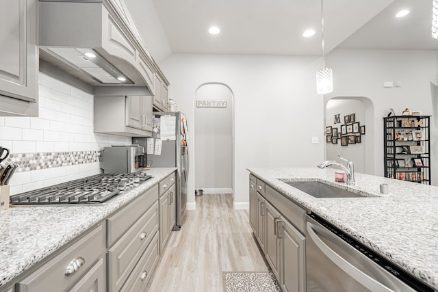 kitchen with sink, hanging light fixtures, stainless steel appliances, tasteful backsplash, and custom exhaust hood