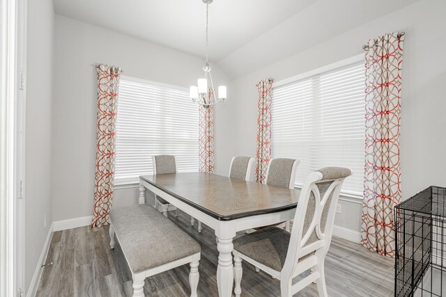 dining room featuring hardwood / wood-style floors, an inviting chandelier, and vaulted ceiling