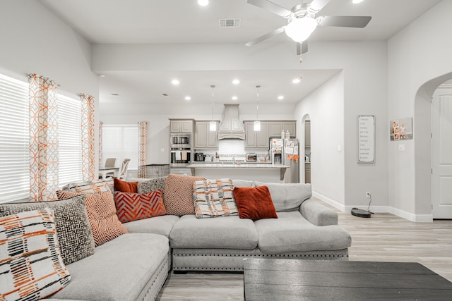 living room with light wood-type flooring, ceiling fan, and sink