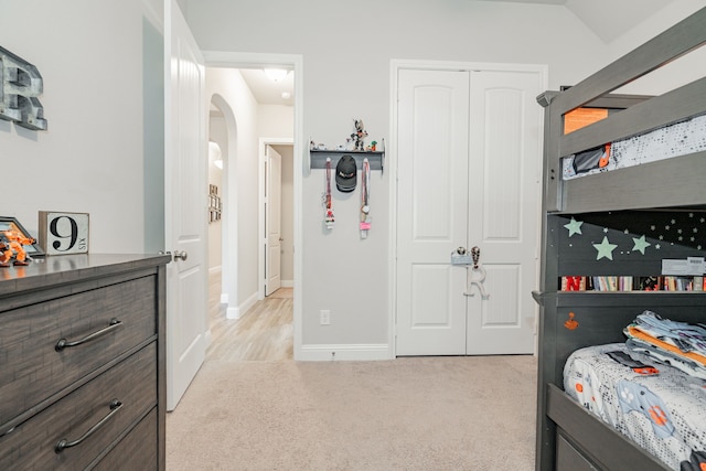 bedroom with lofted ceiling, light carpet, and a closet