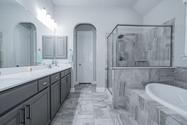 bathroom featuring vanity, separate shower and tub, and vaulted ceiling