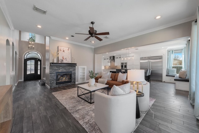 living room with ceiling fan with notable chandelier, dark hardwood / wood-style flooring, a fireplace, and a healthy amount of sunlight