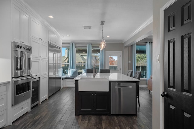 kitchen with stainless steel appliances, a kitchen island, white cabinetry, and sink