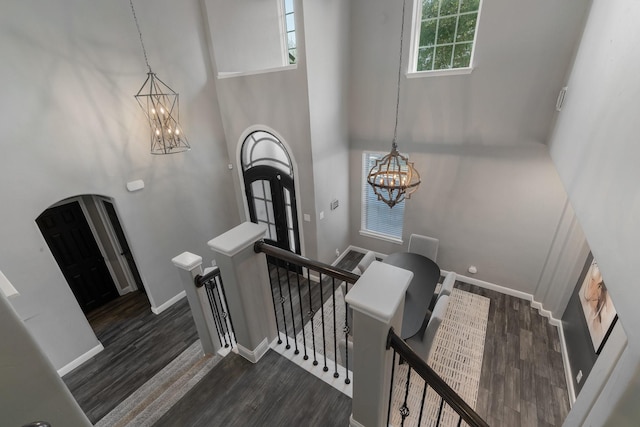 stairs featuring a high ceiling, a chandelier, and hardwood / wood-style floors