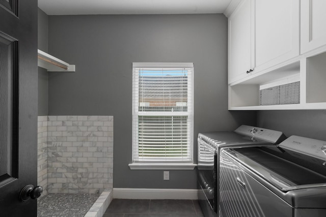 laundry area with cabinets, dark tile patterned flooring, and washing machine and clothes dryer