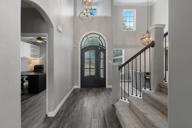 entrance foyer featuring dark hardwood / wood-style flooring, crown molding, and ceiling fan with notable chandelier