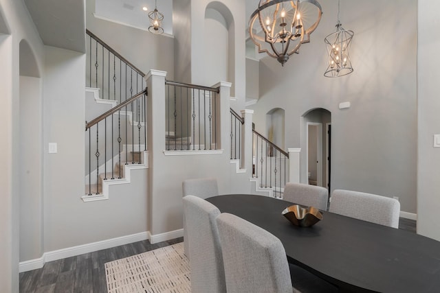 dining area featuring a towering ceiling, an inviting chandelier, and dark hardwood / wood-style floors