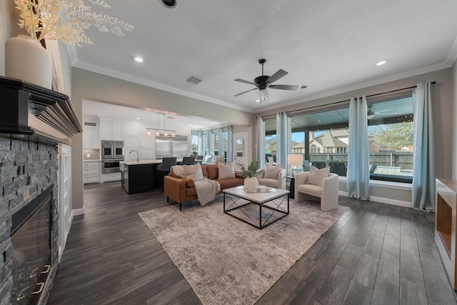 living room featuring ceiling fan, dark hardwood / wood-style floors, ornamental molding, and a fireplace