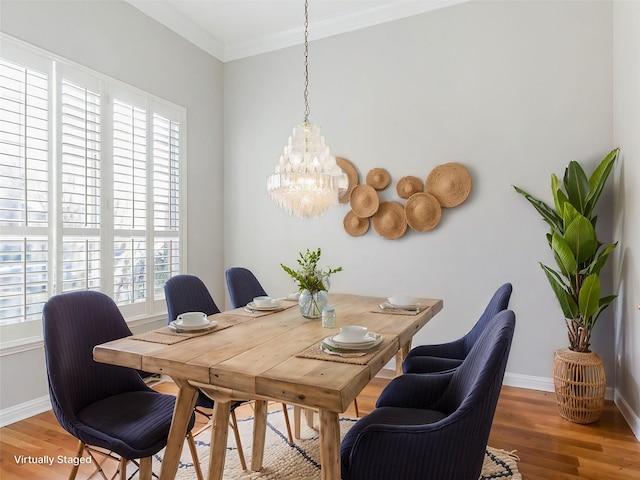 dining area with a wealth of natural light, hardwood / wood-style floors, an inviting chandelier, and ornamental molding