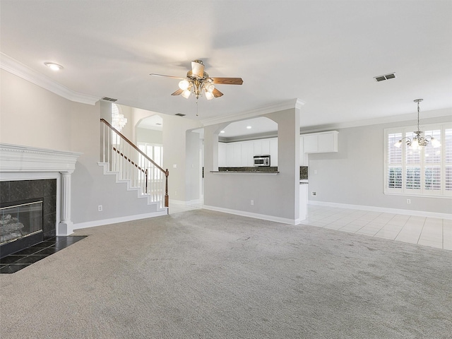 unfurnished living room featuring a fireplace, carpet floors, ceiling fan with notable chandelier, and ornamental molding