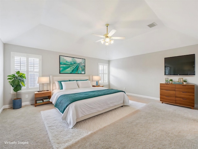 carpeted bedroom with a raised ceiling and ceiling fan