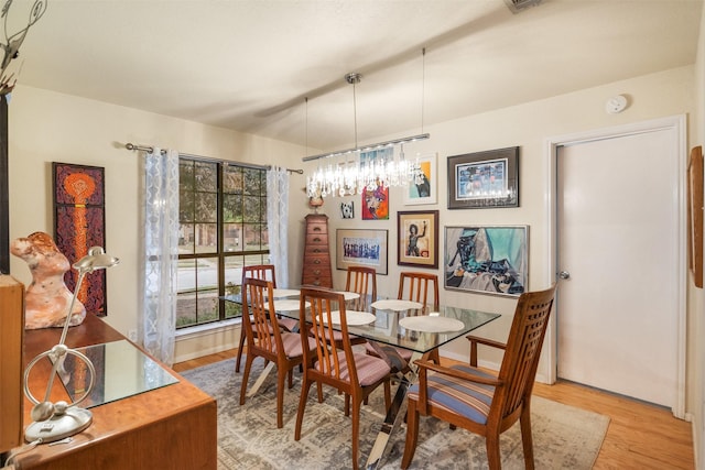 dining area featuring light hardwood / wood-style flooring and a notable chandelier