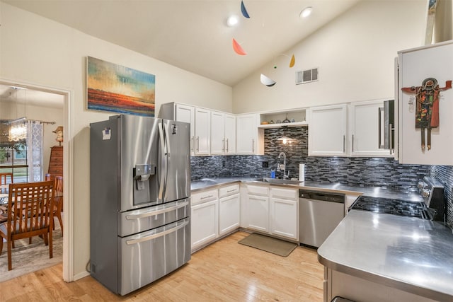 kitchen with sink, light hardwood / wood-style flooring, hanging light fixtures, stainless steel appliances, and white cabinets