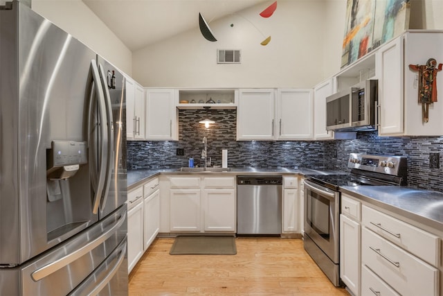 kitchen featuring white cabinetry, sink, stainless steel appliances, tasteful backsplash, and light hardwood / wood-style floors