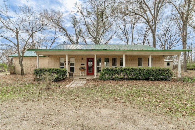 view of front of house featuring brick siding, a porch, and metal roof