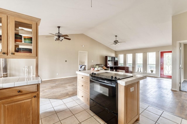 kitchen with tile countertops, ceiling fan, black range with electric stovetop, and light tile patterned floors