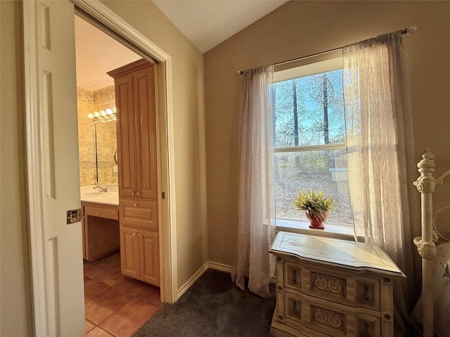 hall with light tile patterned flooring, lofted ceiling, and sink