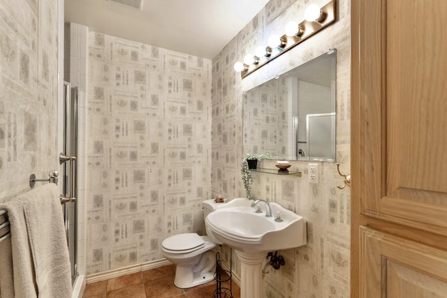 bathroom featuring tile patterned flooring, a shower with shower door, and toilet