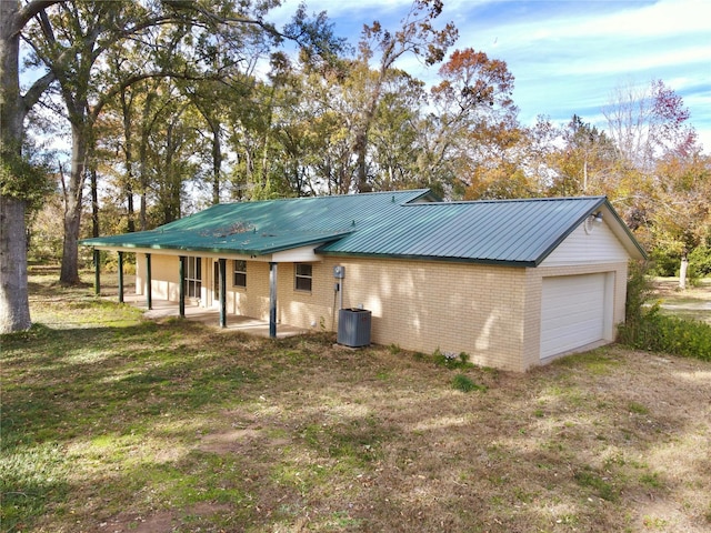 back of property featuring a garage, a lawn, central air condition unit, and covered porch