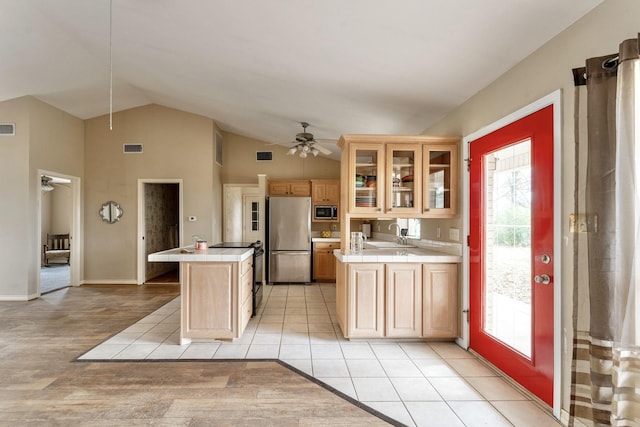 kitchen featuring tile counters, lofted ceiling, stainless steel appliances, a ceiling fan, and a sink