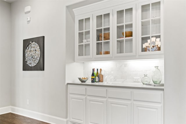 bar with tasteful backsplash, white cabinets, and dark hardwood / wood-style floors