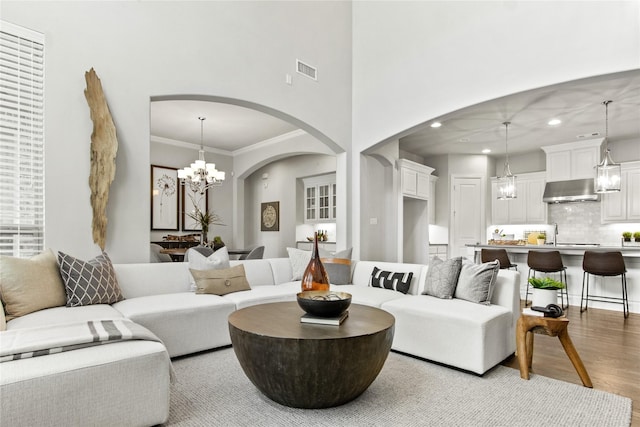 living room with light hardwood / wood-style flooring, a chandelier, and ornamental molding