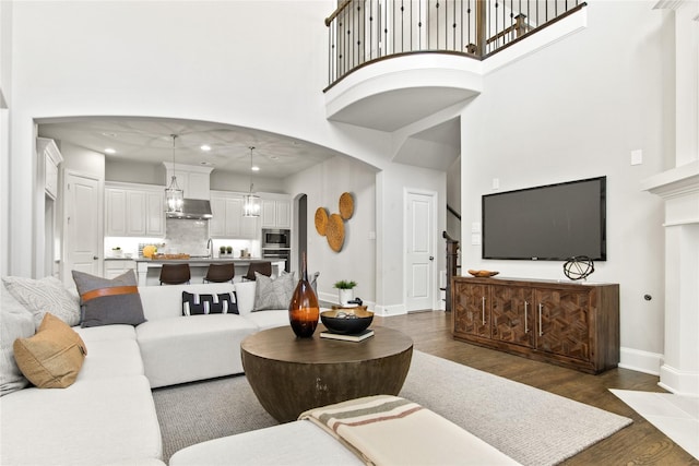 living room featuring a towering ceiling, dark hardwood / wood-style floors, and sink