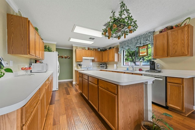 kitchen featuring crown molding, a center island, a skylight, white appliances, and hardwood / wood-style floors