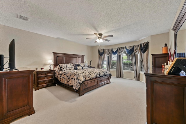 bedroom with ceiling fan, light colored carpet, and a textured ceiling