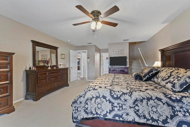 bedroom featuring ceiling fan, light colored carpet, and a textured ceiling