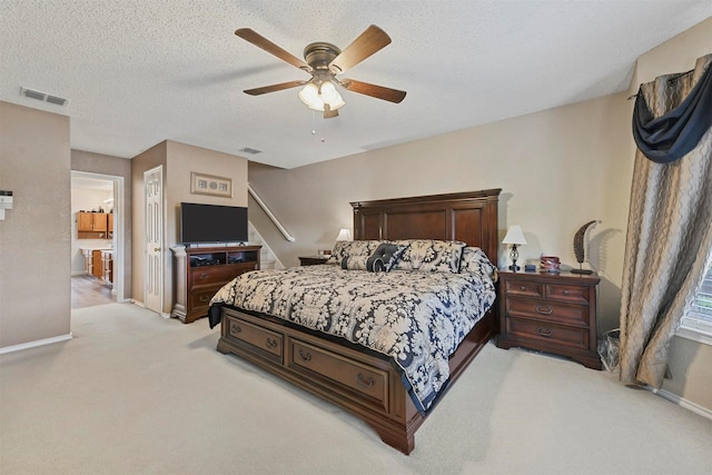 bedroom with ceiling fan, light carpet, and a textured ceiling