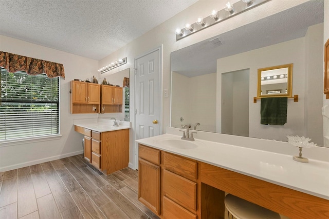 bathroom with hardwood / wood-style flooring, vanity, and a textured ceiling