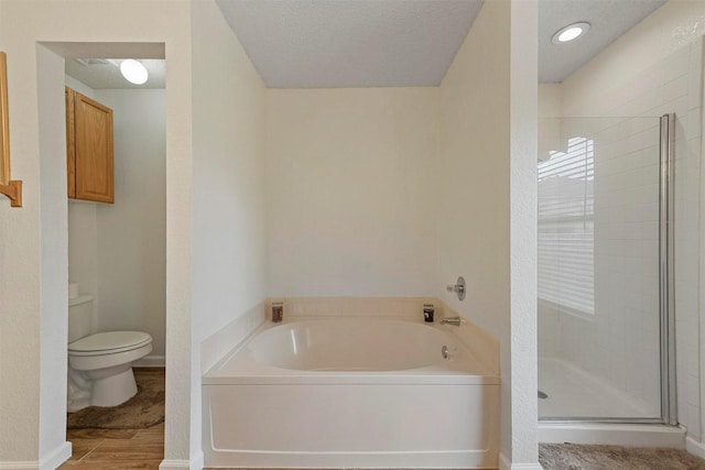 bathroom featuring toilet, independent shower and bath, and a textured ceiling