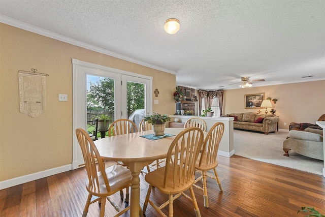 dining space with ceiling fan, ornamental molding, wood-type flooring, and a textured ceiling