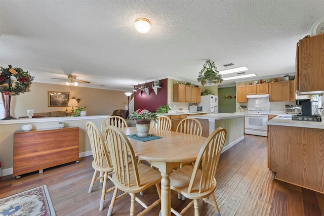 dining space featuring ceiling fan, a textured ceiling, and light wood-type flooring