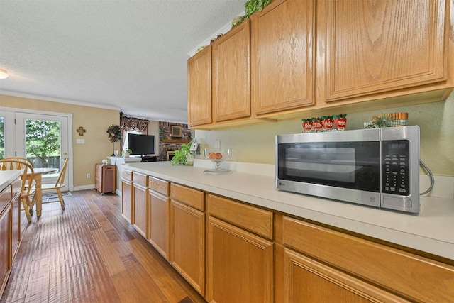 kitchen featuring hardwood / wood-style flooring, ornamental molding, and a textured ceiling