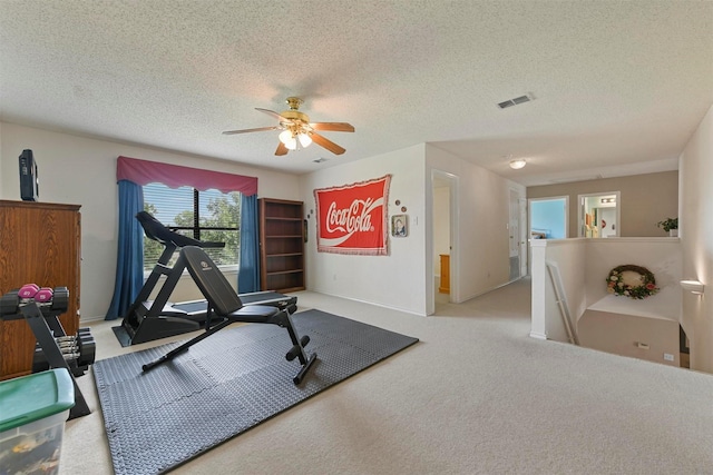 exercise area with light carpet, ceiling fan, and a textured ceiling