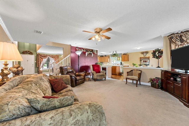 carpeted living room with crown molding, ceiling fan, and a textured ceiling