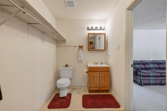 bathroom with vanity, a textured ceiling, and toilet