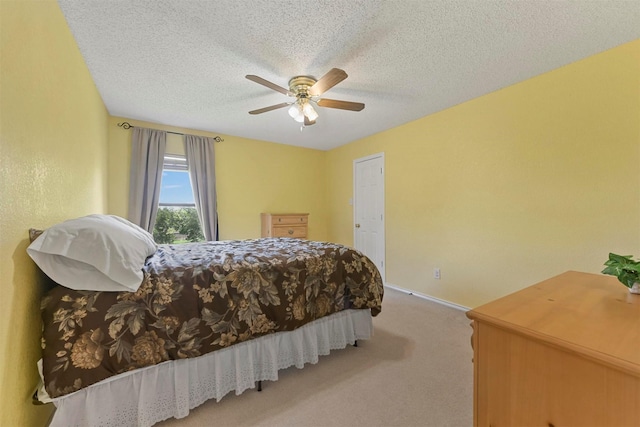 bedroom with light carpet, ceiling fan, and a textured ceiling