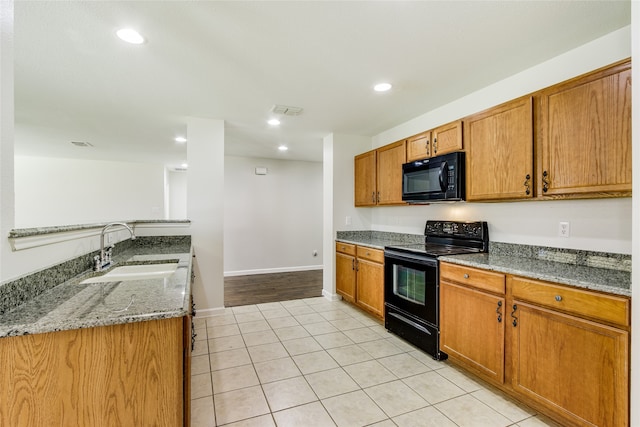 kitchen featuring stone counters, sink, light tile patterned floors, and black appliances