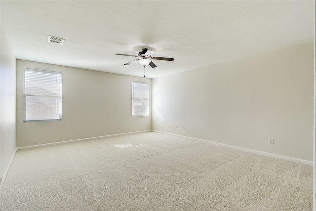 spare room with ceiling fan, light colored carpet, and a healthy amount of sunlight