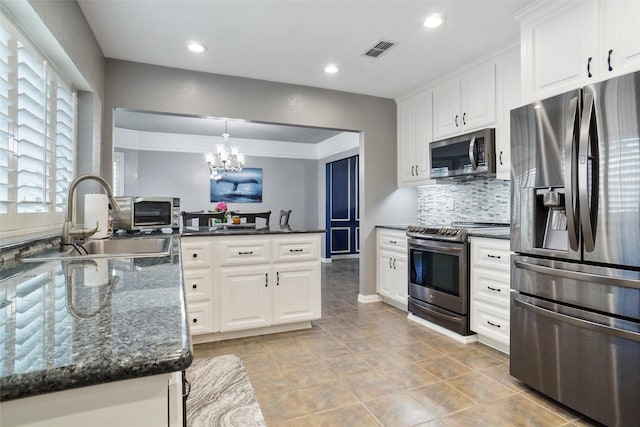 kitchen featuring sink, white cabinetry, stainless steel appliances, a notable chandelier, and decorative light fixtures