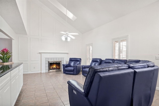 living room featuring light tile patterned floors, a decorative wall, a tile fireplace, and a ceiling fan