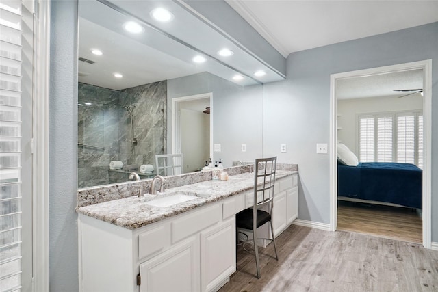 bathroom with vanity, wood finished floors, baseboards, recessed lighting, and a tile shower